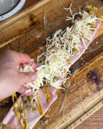 the making of a crispy cuban rice paper sandwich, with roasted pork, mustard, rice paper sheets, and shredded cheese