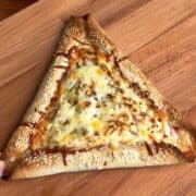 a tortilla breakfast pizza with sausage stuffed crust, covered in melty cheese and sprinkled with sesame seeds