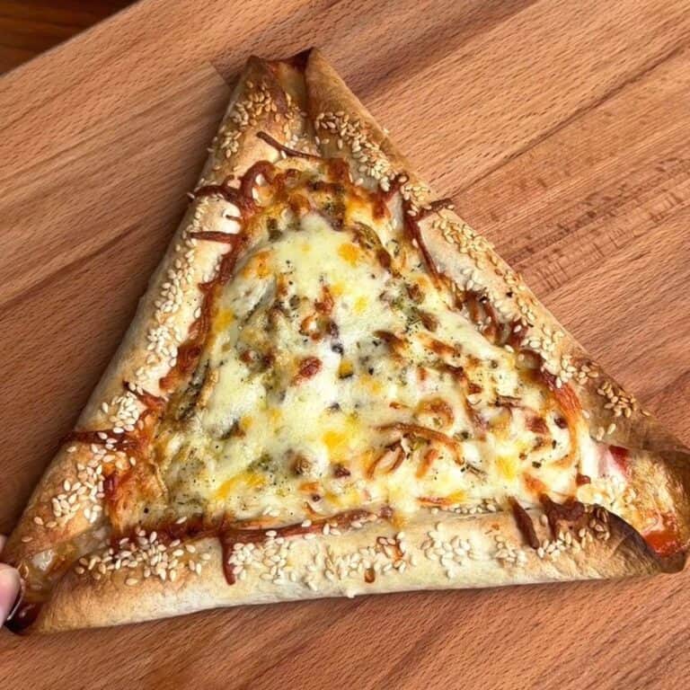 a tortilla breakfast pizza with sausage stuffed crust, covered in melty cheese and sprinkled with sesame seeds