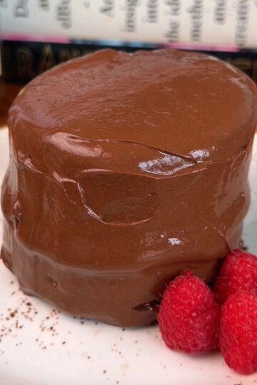 a personal sized high protein chocolate cake on a plate with raspberries