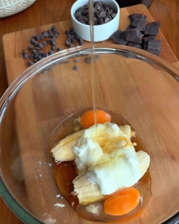 yogurt, banana, egg and maple syrup in a bowl for the making of caramelized banana chocolate chunk blondies