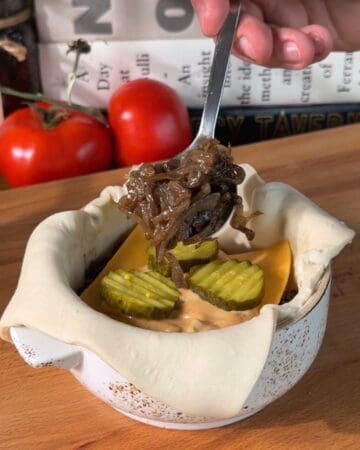 puff pastry, burger patty, pickkles, carmelized onions, and cheddar cheese being layered before baking