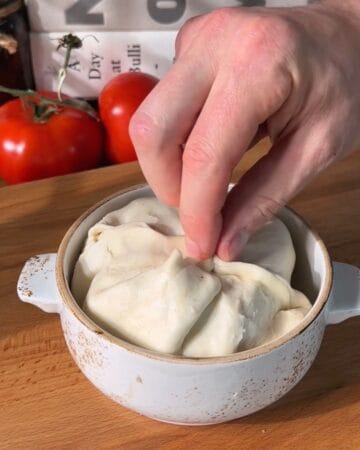 sealing the puff pastry over top the layered cheeseburger wellington ingredients before baking
