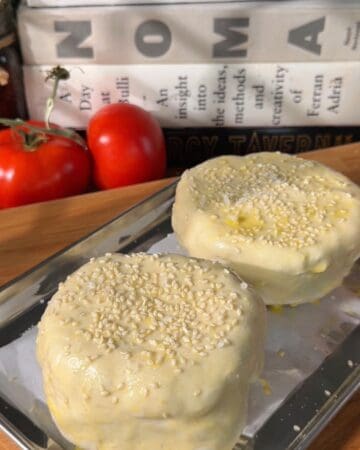 golden puff pastry cheeseburger wellington on parchment with sesame seeds and flaky salt