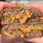 cheeseburger wellington sliced in half showing layers of burger patty cheddar and caramelized onions