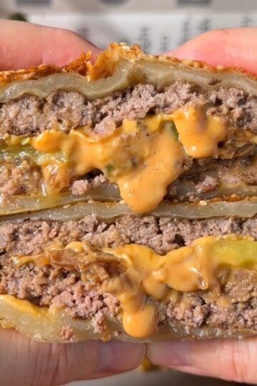 cheeseburger wellington sliced in half showing layers of burger patty cheddar and caramelized onions