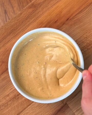 a garlicky yogurt sauce being mixed in a bowl as topping for a chicken shawarma wrap