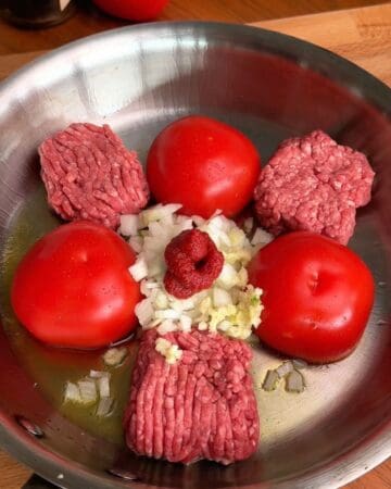 beef, onions, tomatoes and tomato paste in pan