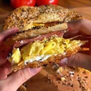 crispy rice paper bacon egg and cheese sandwich sliced in half, so the layers of bacon, egg, cream cheese and cheddar are visible