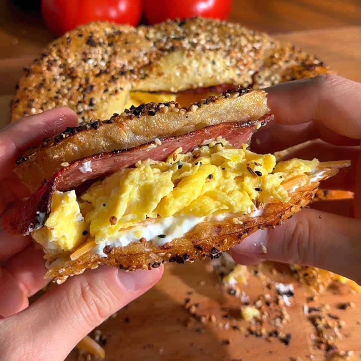 crispy rice paper bacon egg and cheese sandwich sliced in half, so the layers of bacon, egg, cream cheese and cheddar are visible