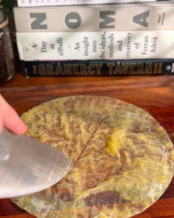 slicing a rice paper sheet, dipped in egg wash, to be folded into a sandwich disc