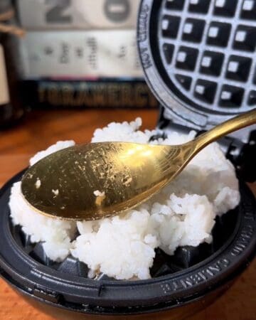 rice being packed down onto a mini waffle maker with a spoon