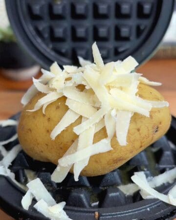a small baked potato in a waffle maker, sprinkled with cheese
