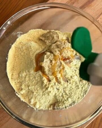 almond flour, maple syrup, being added to a bowl for the making of high protein cookie dough