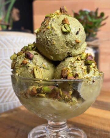 high protein pistachio ice cream sundae topped with crushed pistachios and a maple syrup drizzle