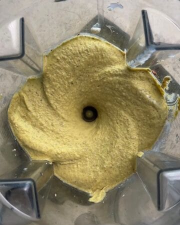 cottage cheese, maple syrup and pistachios being blended in a blender for 3 ingredient high protein pistachio ice cream