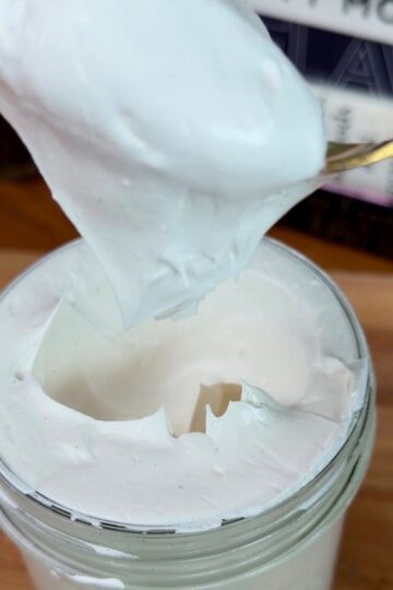 homemade marshmallow fluff on a spoon, overflowing out of a jar