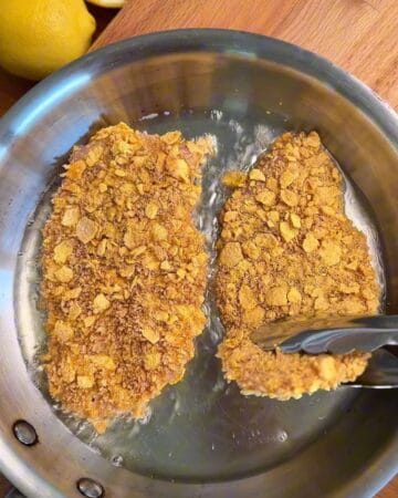 crispy cornflake panko crusted chicken cutlets sizzling in a pan