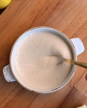 Greek yogurt Caesar dressing in bowl with anchovies and Parmesan