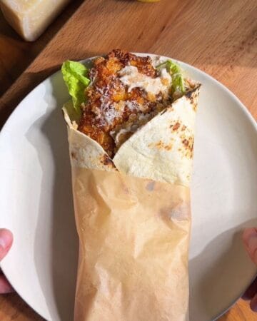 hot honey cornflake chicken Caesar wrap on a plate and wrapped in paper