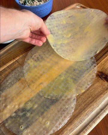three rice paper discs, dipped in egg wash, laid on a cutting board