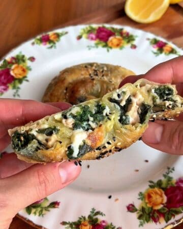 a baked, rice paper spanakopita spiral, cut in half so the insides are visible: melty cheese, spinach and chicken