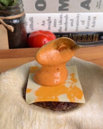 sausage, cheese, and burger sauce being layered into a puff pastry for a breakfast sandwich wellington