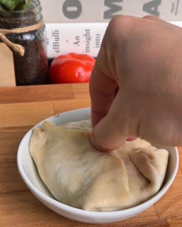 puff pastry being sealed up around a breakfast sandwich wellington before it goes in the oven
