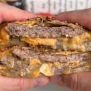 breakfast sandwich wellington sliced in half so layers are visible, with melty cheese, juicy sausage patty, and runny egg