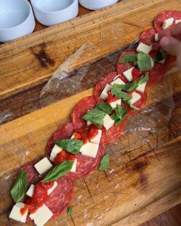 pepperoni, mozzarella, tomato sauce and basil on top of rice paper sheets, for the making of pepperoni pizza rice paper spiral