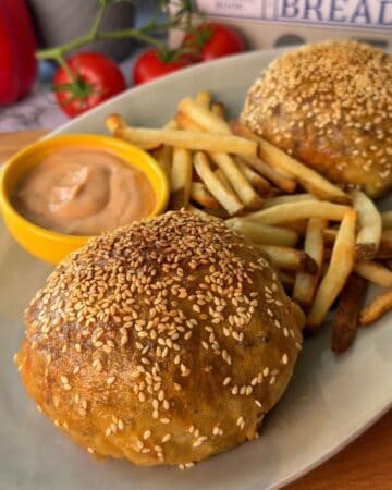 Delicious cheeseburgers topped with sesame seeds, served with crispy fries and dipping sauce. Perfec.