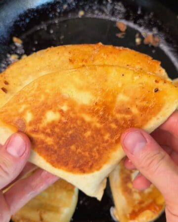 a folded smashburger tortilla being grilled on a pan so it gets crispy and golden brown