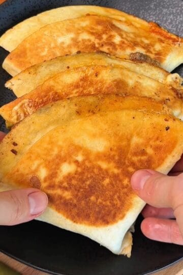 a plate of golden brown, folded crispy smashburger tortillas stuffed with beef and cheese ready to be eaten