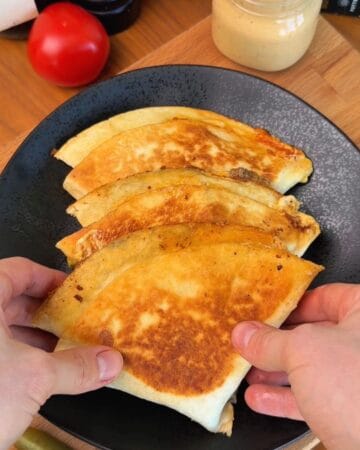 a plate of crispy, golden brown, smash burger quesadillas stuffed with seasoned ground beef and melted cheese