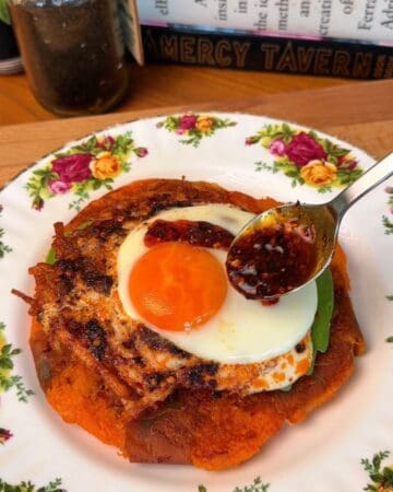 a crispy, smashed sweet potato pancake, layered with egg, fanned avocado and chili crisp