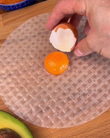 an egg yolk being placed on a rice paper sheet for the making of crispy spicy salmon rice paper tostada