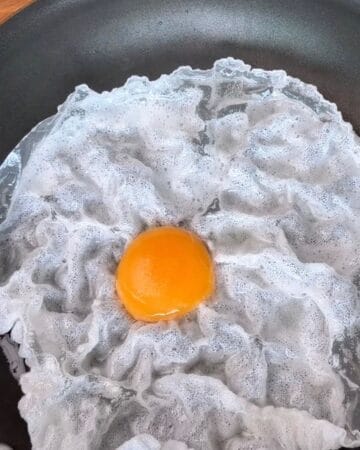rice paper sheet in a frying pan, with an egg yolk in the center, for the making of a crispy rice paper tostada