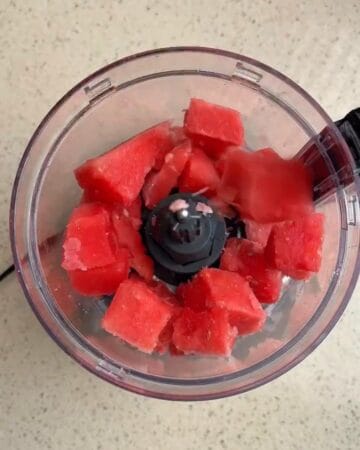 Watermelon chunks in a blender for a refreshing sorbet.