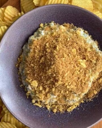 fried pickle dip spread in a shallow dish topped with toasted panko and crushed kettle chips