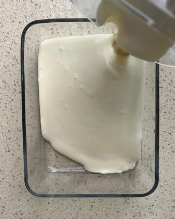 Cream being poured into a glass container for homemade ice cream.