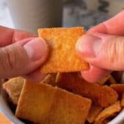 homemade cheez-it cracker made from almond flour and cheddar cheese being held by a person