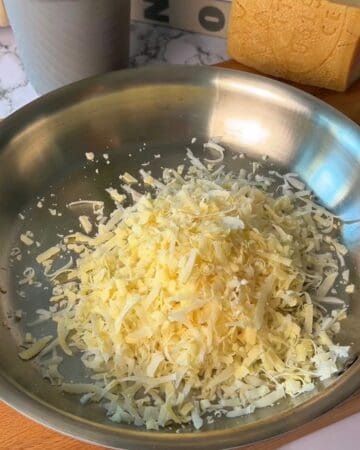 Close-up of shredded cheese in a stainless steel pan for cooking or baking.
