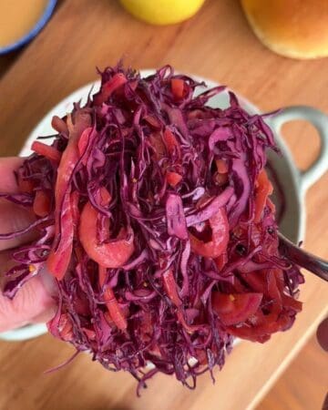 pickled cabbage and red onion slaw with dill pickles being tossed in vinegar dressing