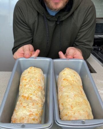 two cheddar loaves in oiled loaf pans rising for 25 minutes until puffed