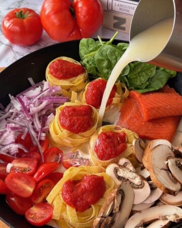 Onion, spinach, pasta, marinara, salmon, cream, broth in a pan for one pan creamy tomato pasta