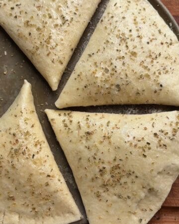 tortilla pizza pockets brushed with olive oil and sprinkled with italian seasoning on baking sheet