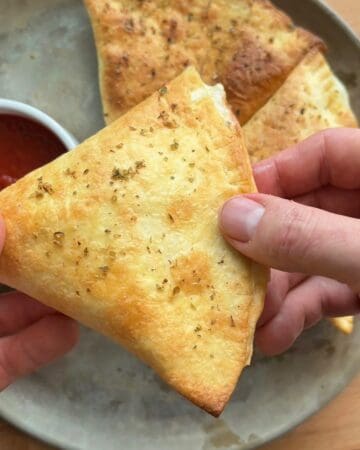 Close-up of a crispy tortilla pizza pockets on a tray, sprinkled with Italian seasoning