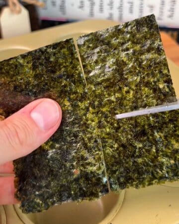 Close-up of seaweed being sliced into quarters for salmon sushi cups