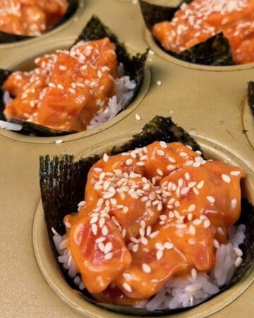 Delicious spicy salmon sushi bites with sesame seeds on rice and nori.
