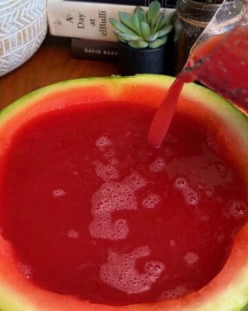 Fresh watermelon juice and gelatin being poured back into the watermelon rind to set in the fridge for watermelon jello
